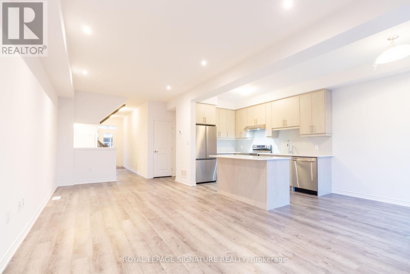 A spacious kitchen with white cabinets and a wooden floor.