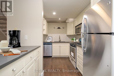 A modern kitchen with a stainless steel refrigerator and wooden floors.