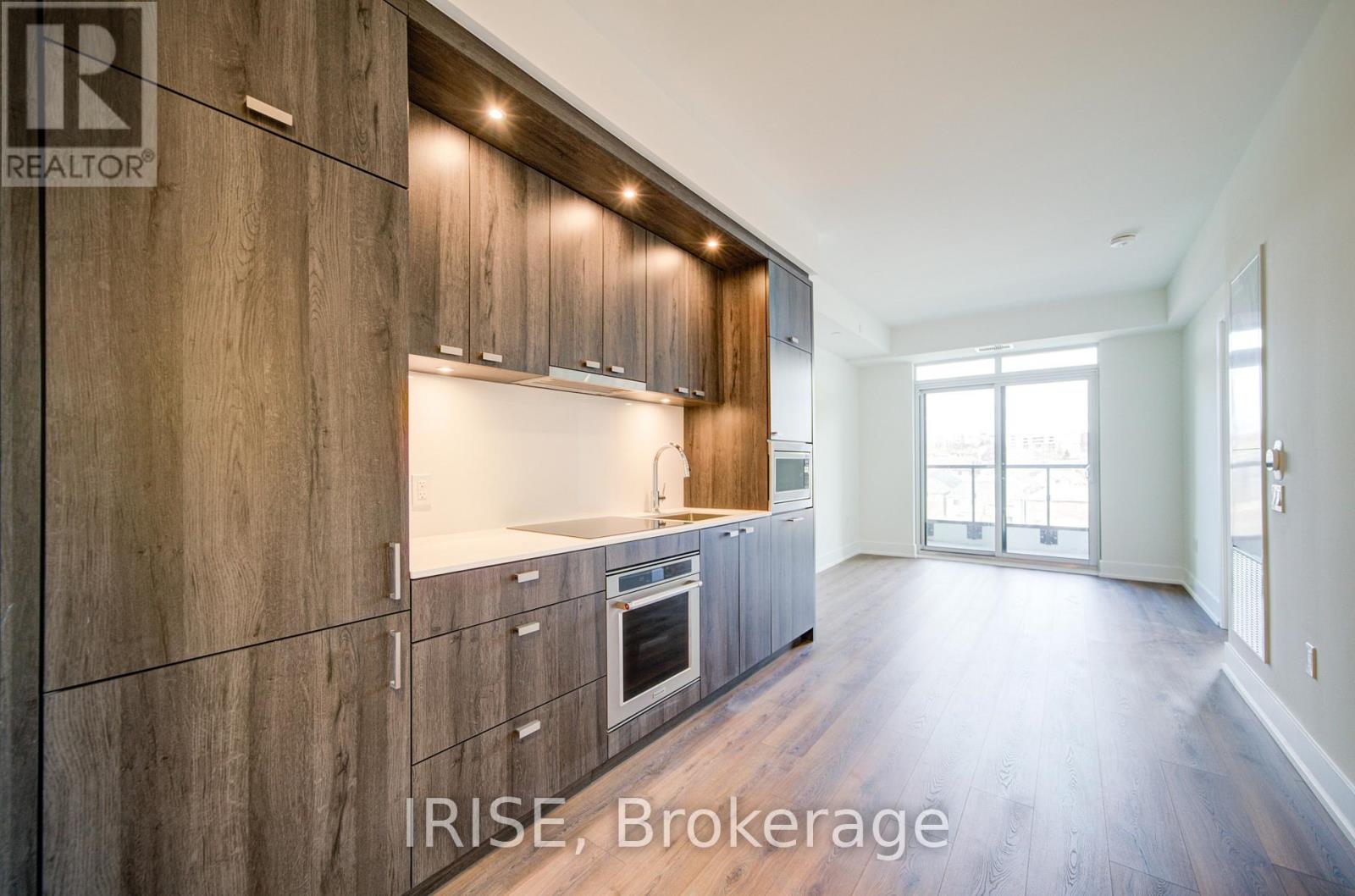 A modern kitchen with wooden cabinets and a large window.