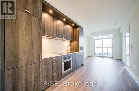 A modern kitchen with wooden cabinets and a large window.