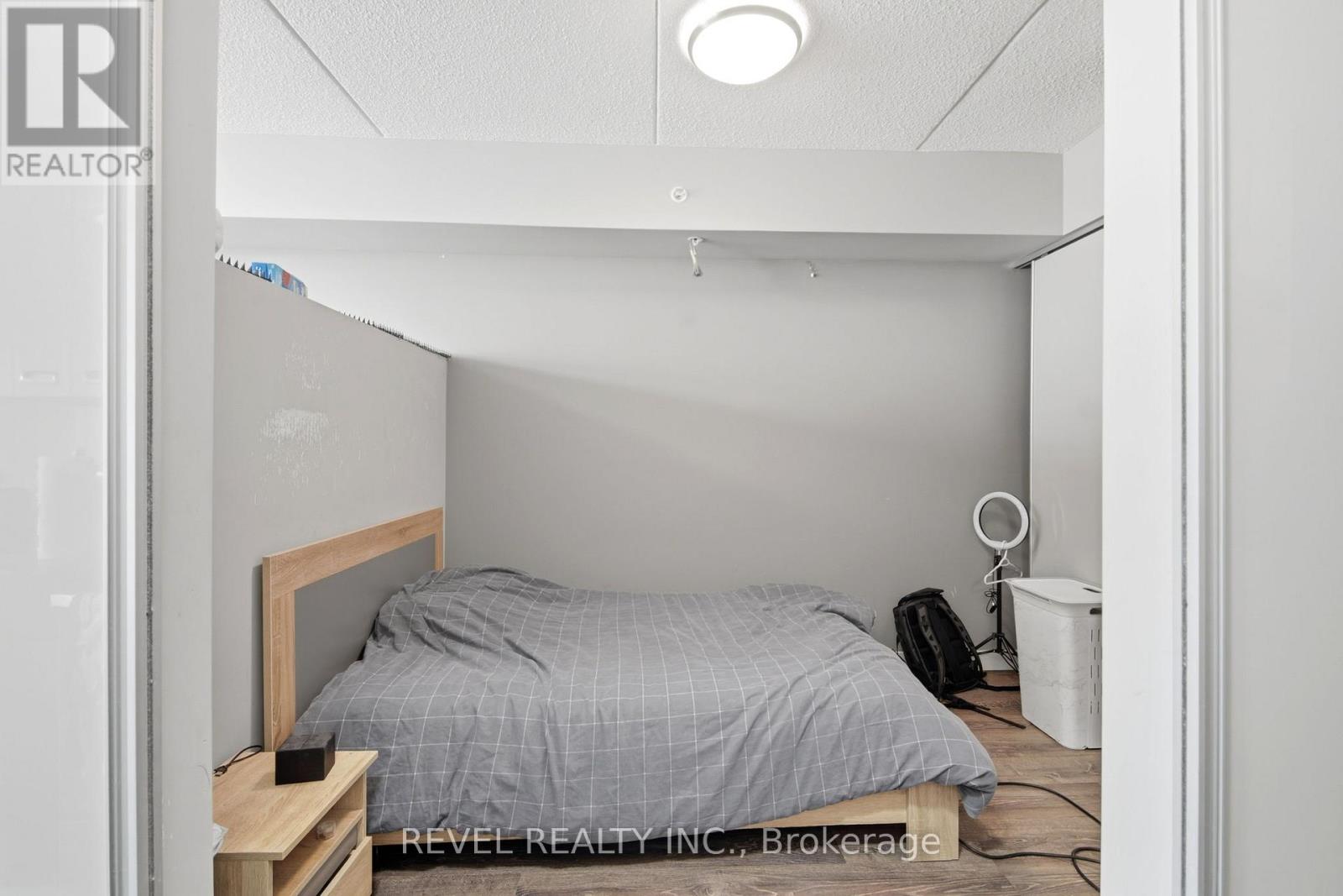 A bedroom with a bed, nightstand, and a fan.