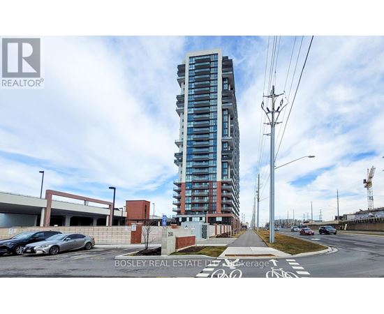 A tall building with a glass facade stands in the middle of a street with cars parked on the side.