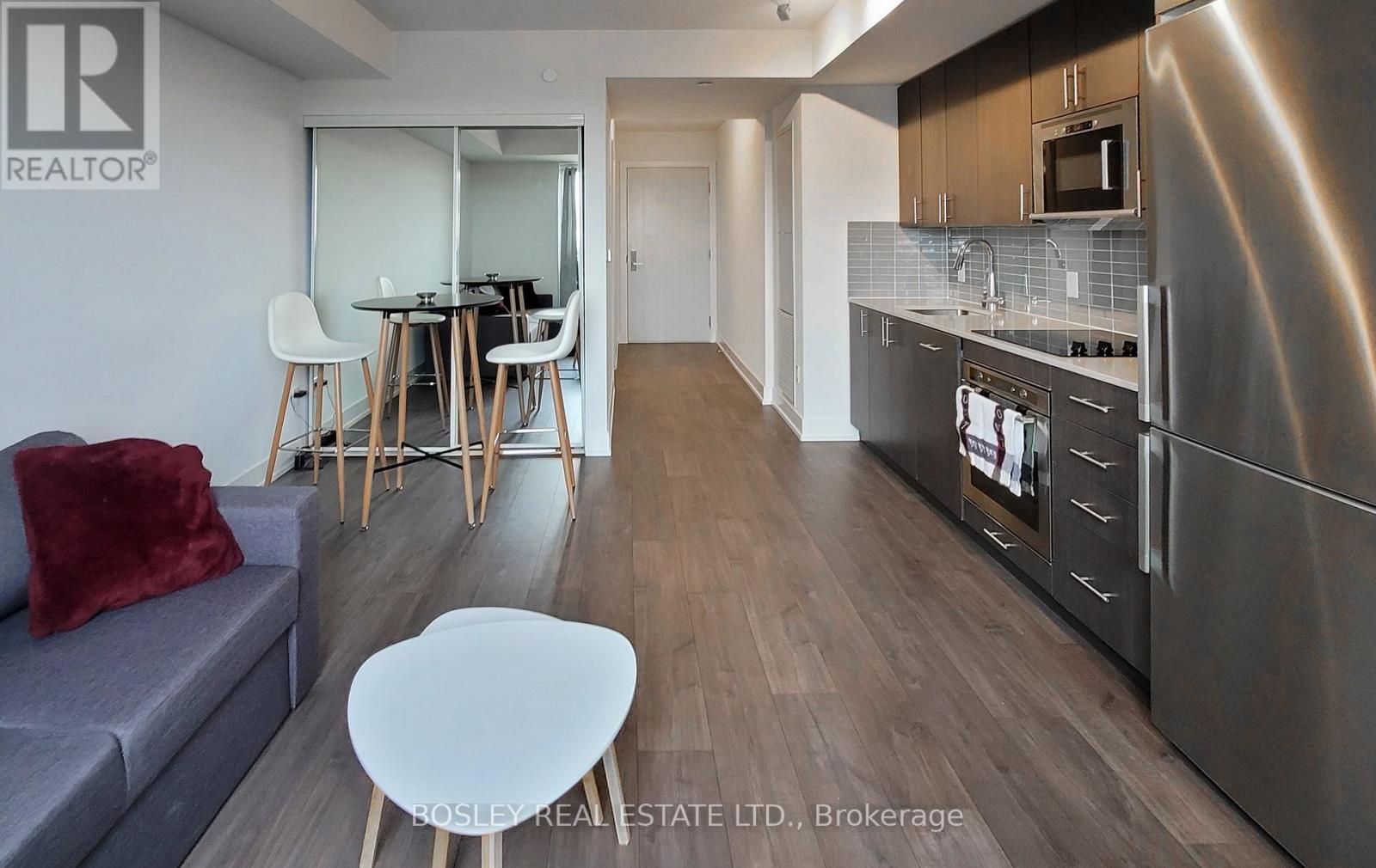 A modern kitchen with stainless steel appliances and a dining area with a table and chairs.