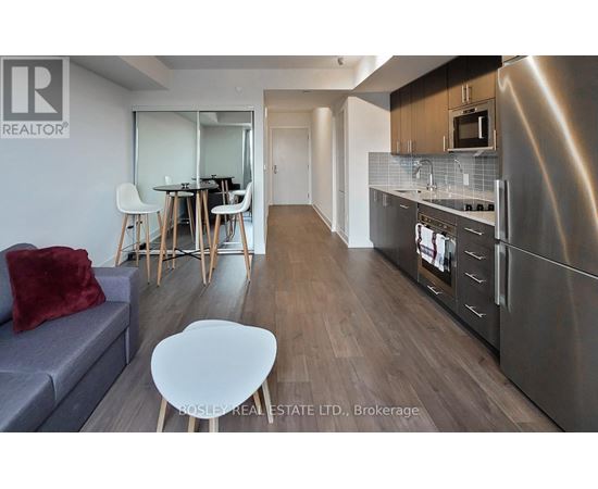 A modern kitchen with stainless steel appliances and a dining area with a table and chairs.