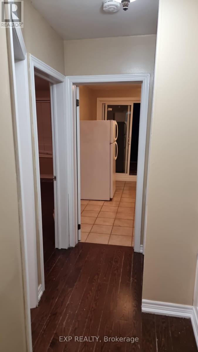 A hallway with a refrigerator in the background.
