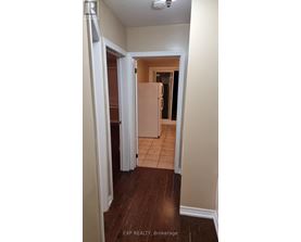 A hallway with a refrigerator in the background.
