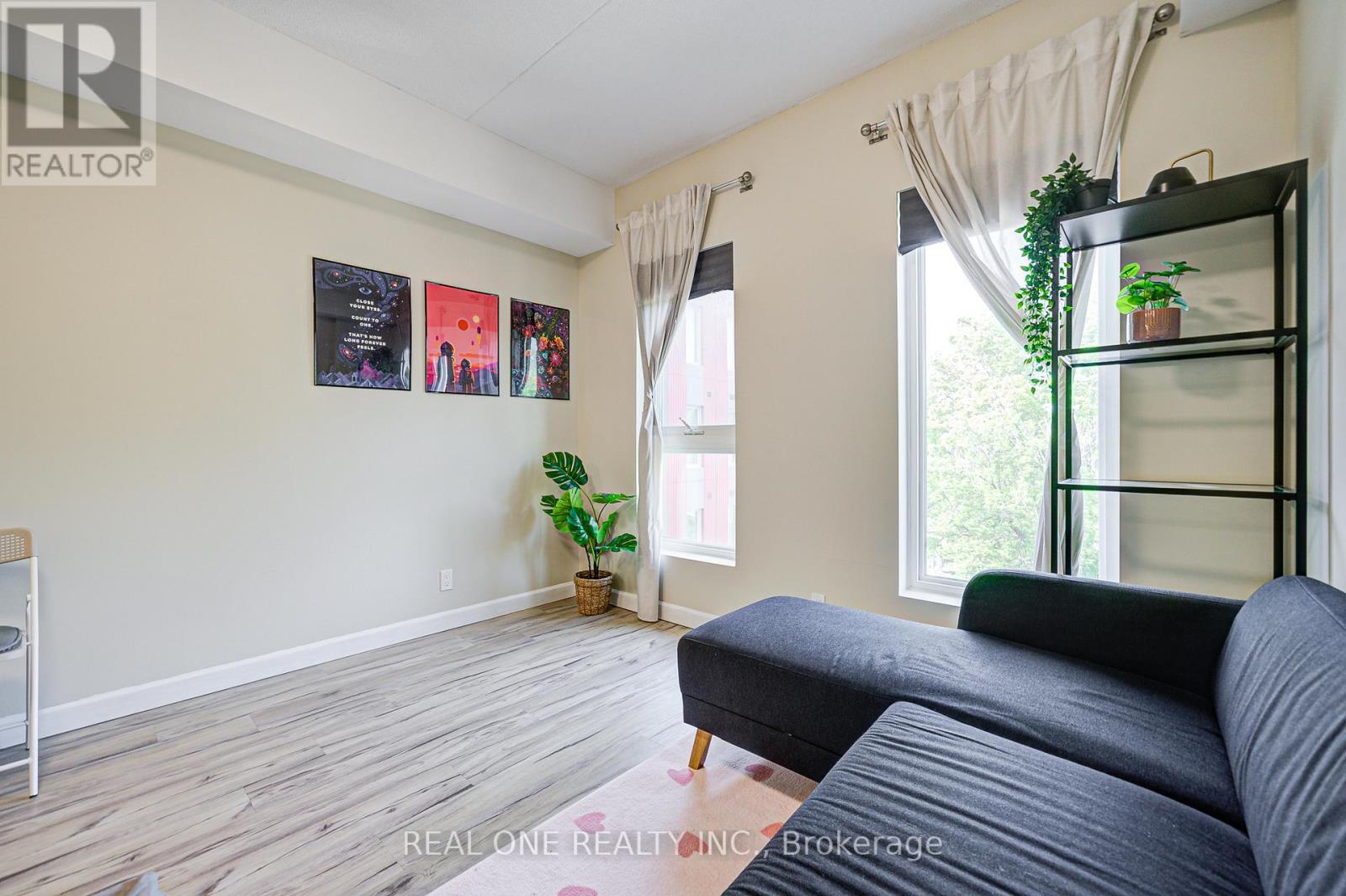 A living room with a grey couch and a plant on a shelf.