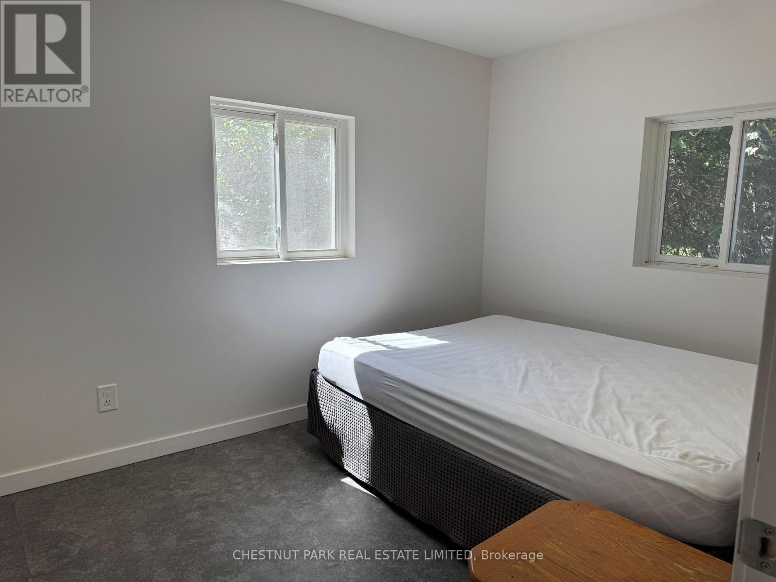 A bedroom with a bed, window, and a wooden table.