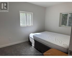 A bedroom with a bed, window, and a wooden table.