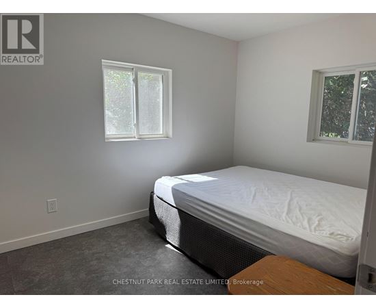 A bedroom with a bed, window, and a wooden table.