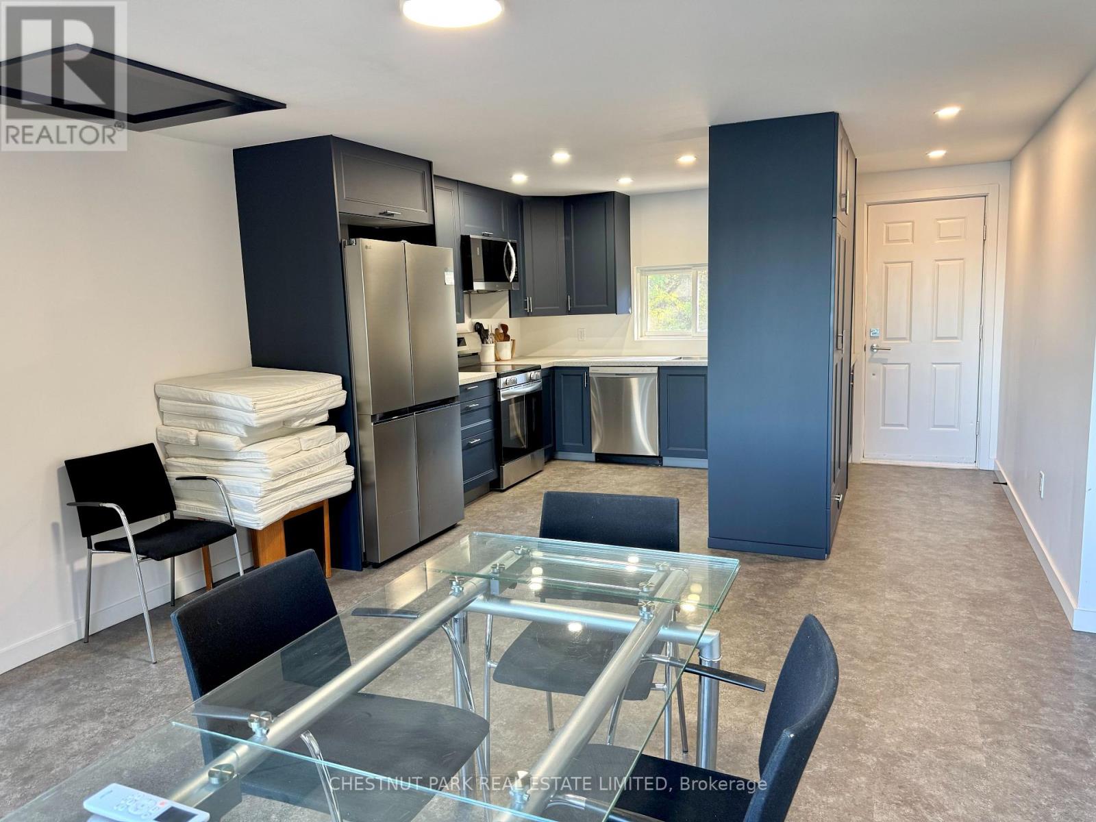 A modern kitchen with a glass table and stainless steel appliances.