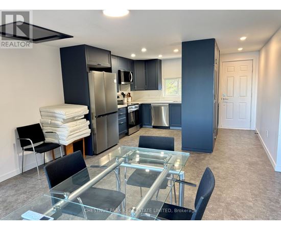 A modern kitchen with a glass table and stainless steel appliances.