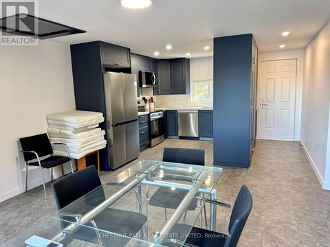 A modern kitchen with a glass table and stainless steel appliances.