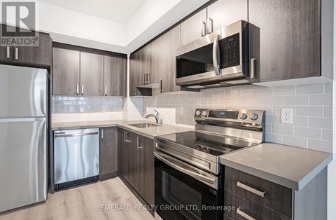 A modern kitchen with dark wood cabinets and stainless steel appliances.