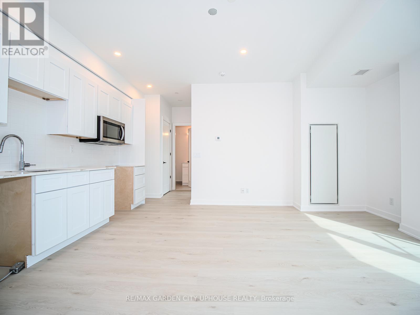 A spacious kitchen with white cabinets and a microwave on the counter.