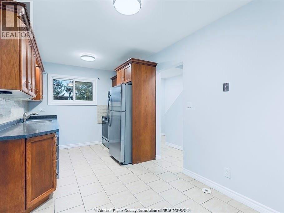 A kitchen with a refrigerator, sink, and cabinets.