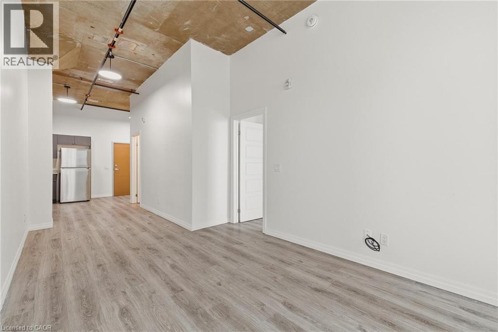 A spacious room with wooden flooring and white walls, ready for a new tenant.
