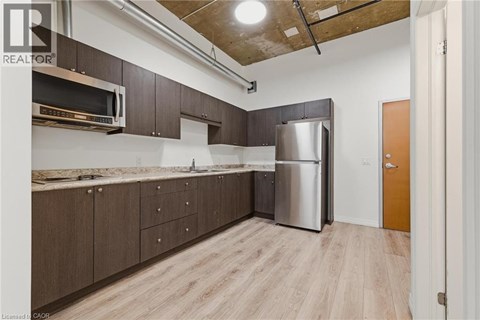 A kitchen with wooden cabinets and a stainless steel refrigerator.