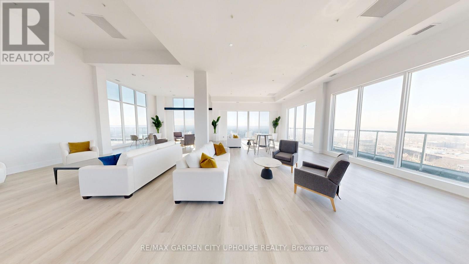 A spacious living room with white furniture and a view of the city.