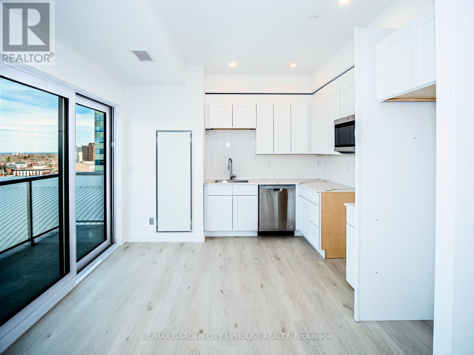 A modern kitchen with white cabinets and a wooden floor.