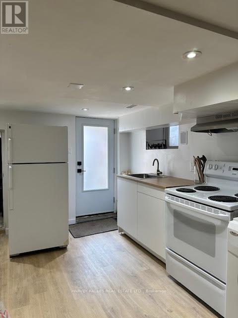 A kitchen with white appliances and wooden floors.