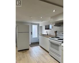 A kitchen with white appliances and wooden floors.