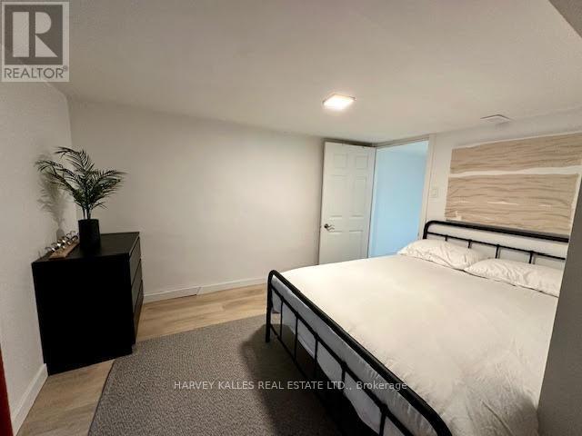 A bedroom with a bed, nightstand, and plant.