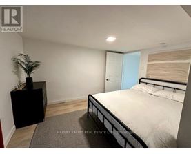 A bedroom with a bed, nightstand, and plant.