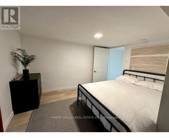 A bedroom with a bed, nightstand, and plant.