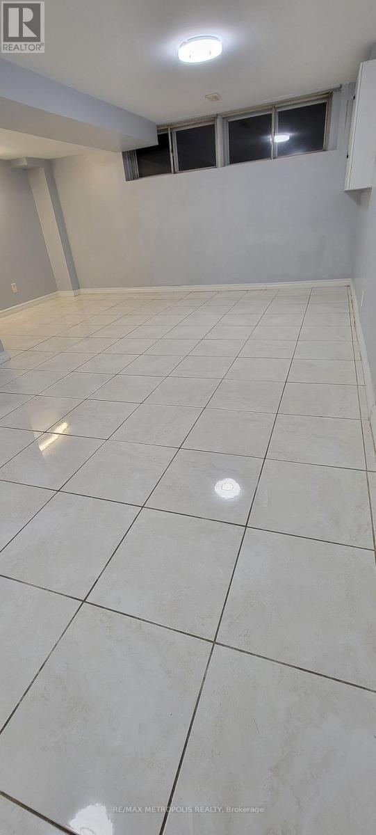 A spacious room with white tiled flooring and a window.