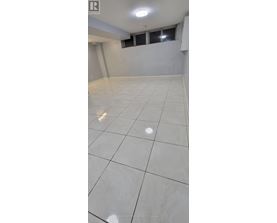 A spacious room with white tiled flooring and a window.