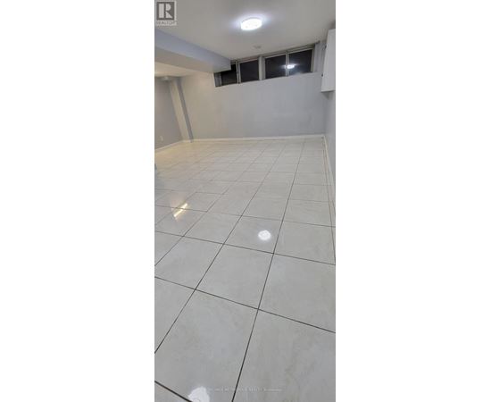 A spacious room with white tiled flooring and a window.
