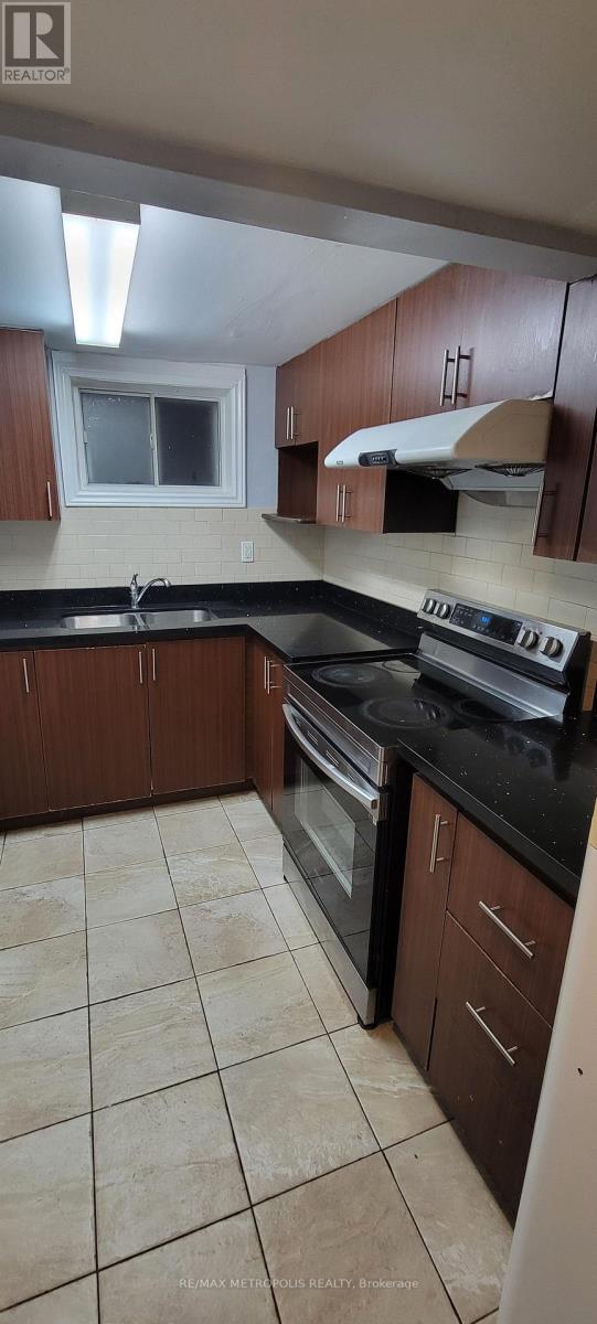 A kitchen with brown cabinets and black countertops.