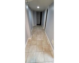 A hallway with tiled floors and a door at the end.
