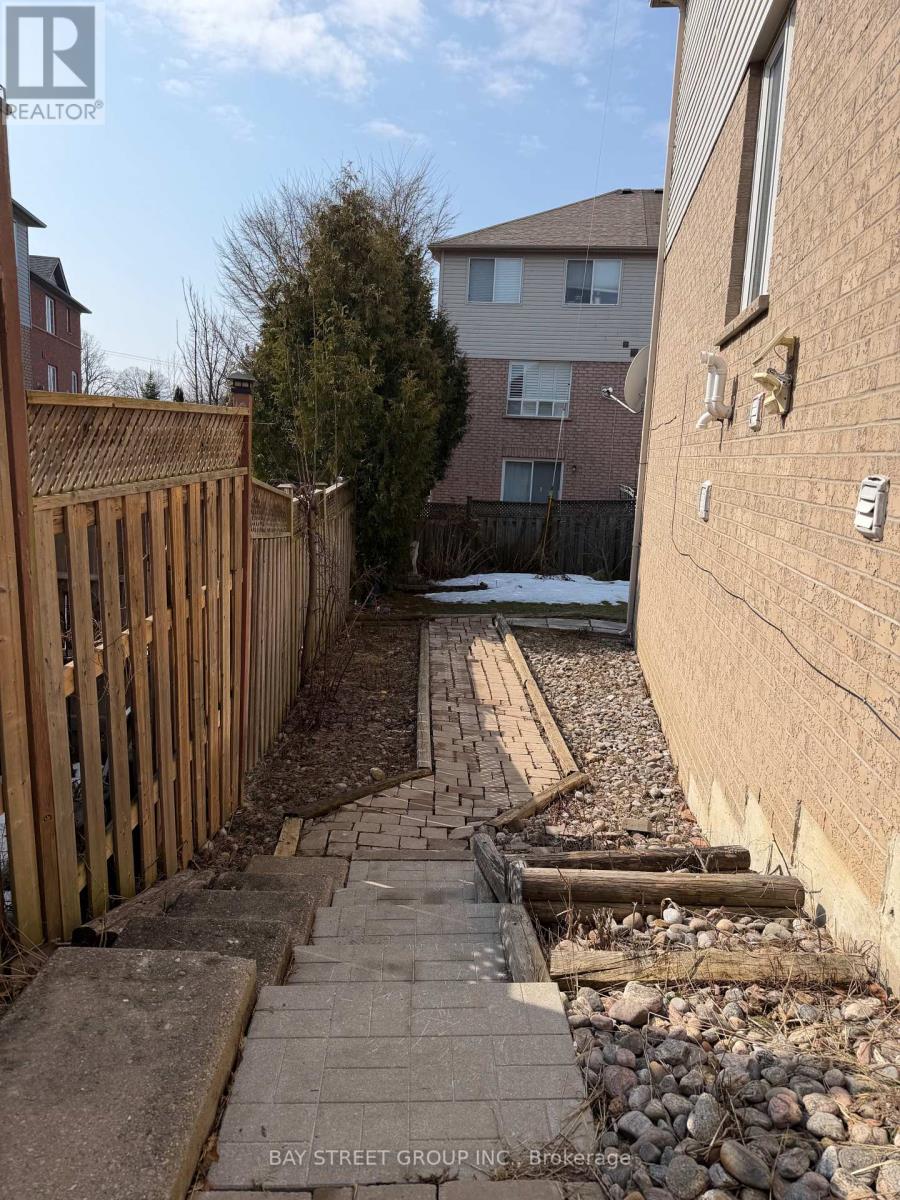 A backyard with a wooden fence and a brick pathway.