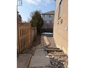 A backyard with a wooden fence and a brick pathway.