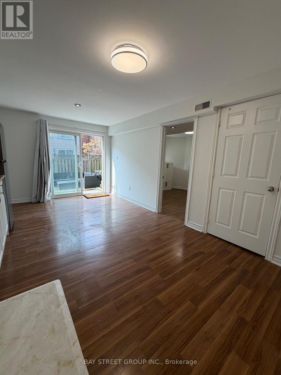 A room with wooden floors and white walls, with a door on the right side.