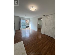 A room with wooden floors and white walls, with a door on the right side.