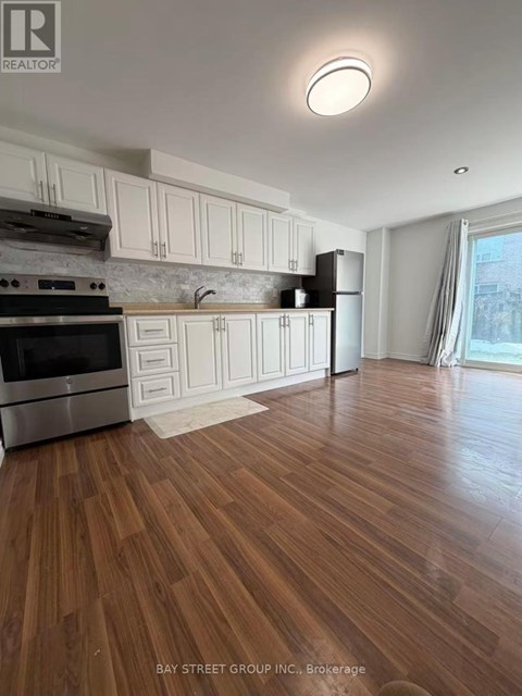 A kitchen with wooden floors and white cabinets.