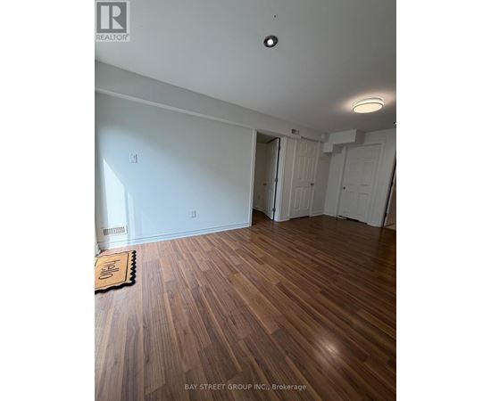 A room with wooden floors and white walls, with a mat on the floor.