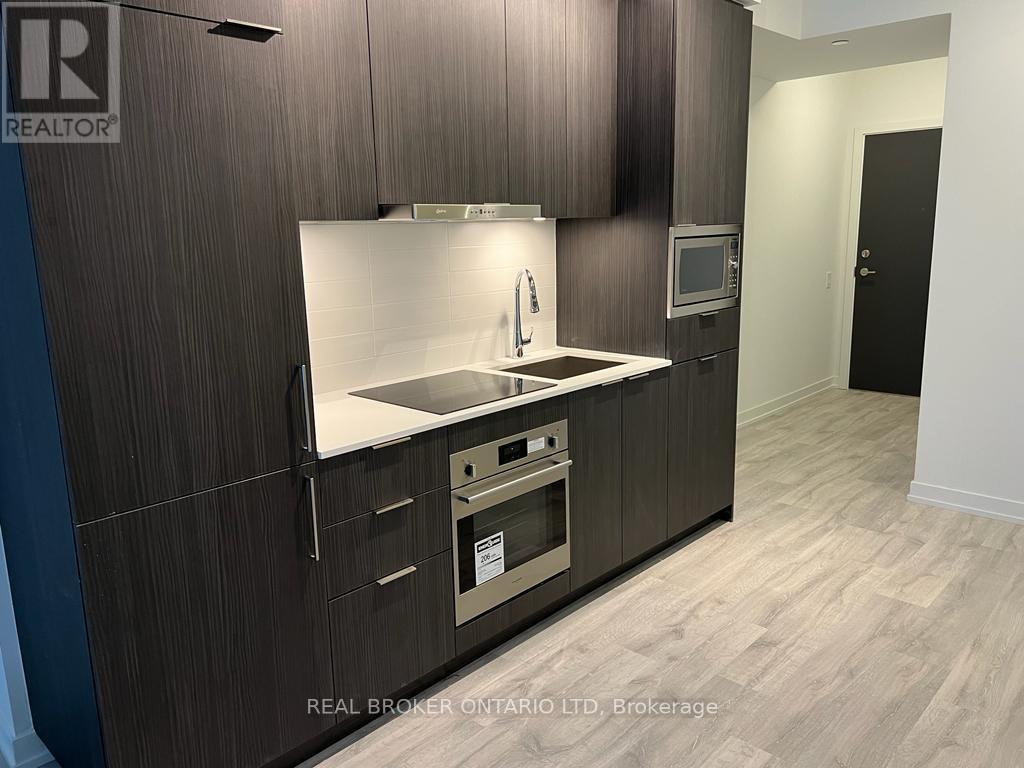 A modern kitchen with dark wood cabinets and a stainless steel sink and oven.
