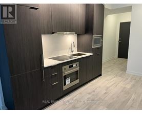 A modern kitchen with dark wood cabinets and a stainless steel sink and oven.