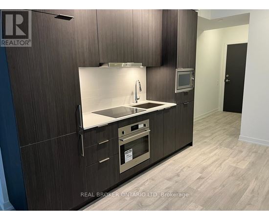 A modern kitchen with dark wood cabinets and a stainless steel sink and oven.