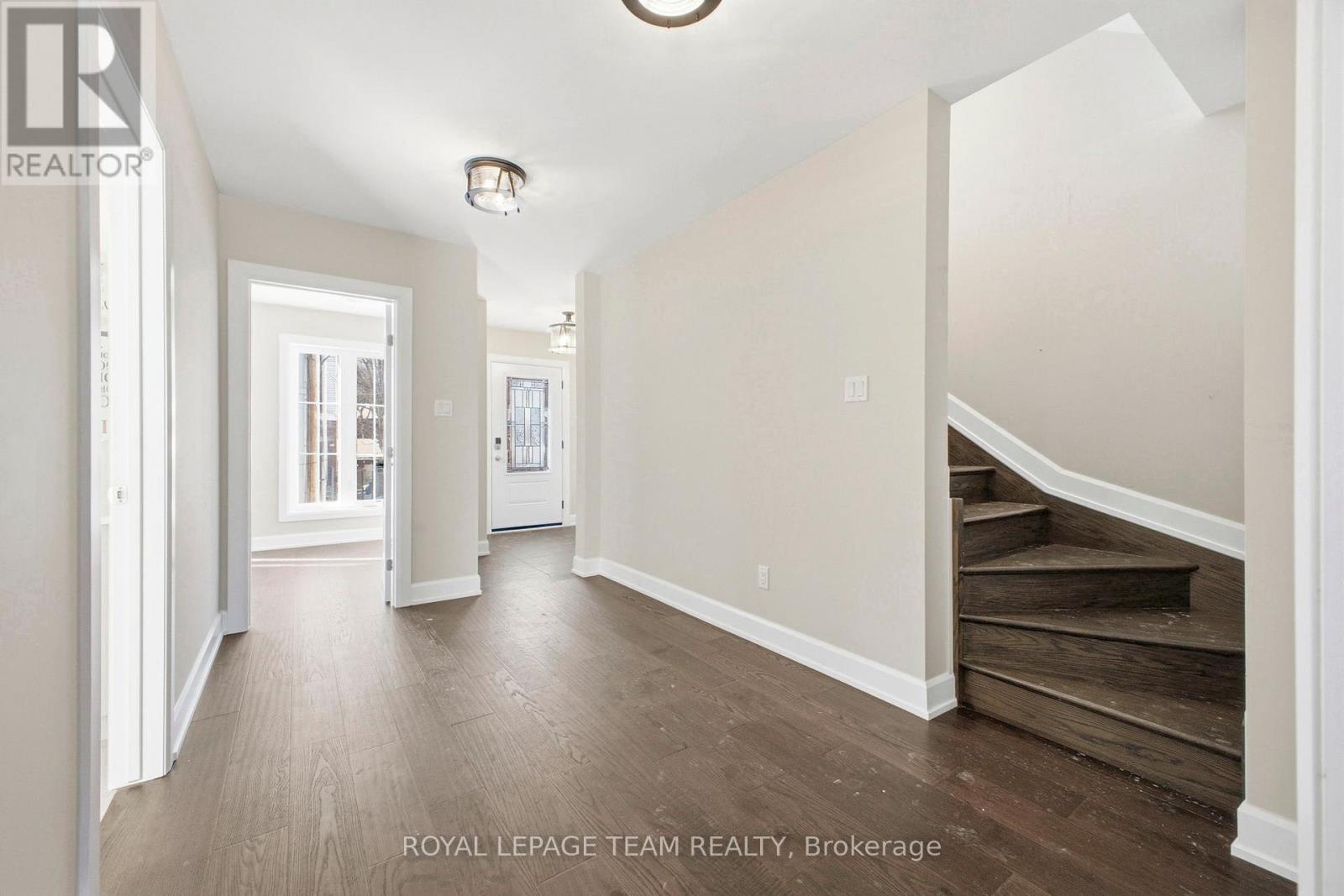 A spacious hallway with wooden floors and white walls.