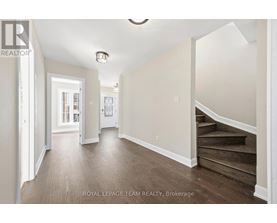 A spacious hallway with wooden floors and white walls.