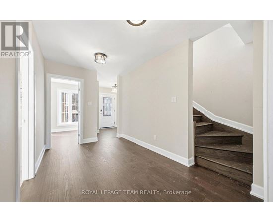 A spacious hallway with wooden floors and white walls.