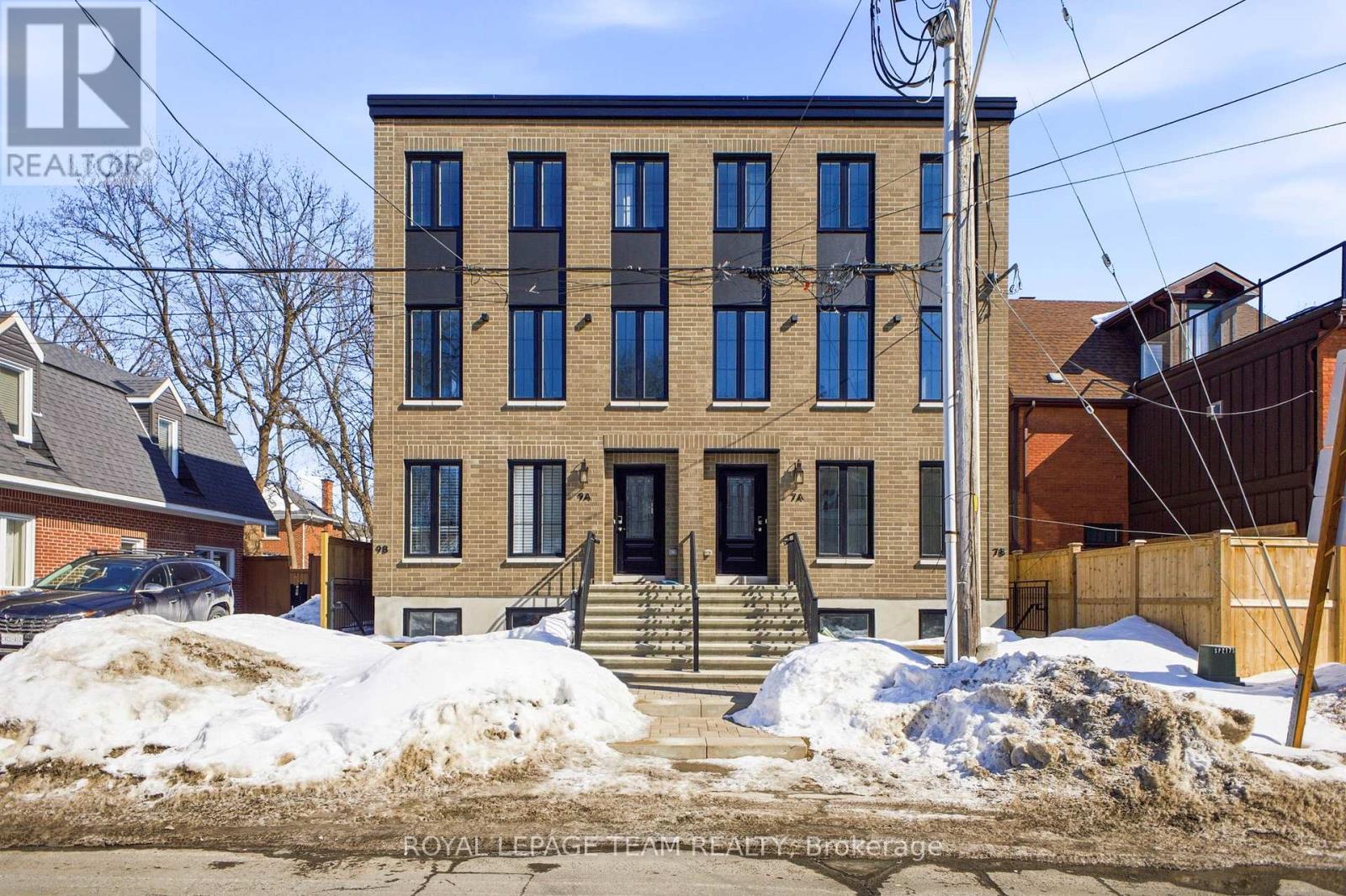 A building with a black door and windows is surrounded by snow.