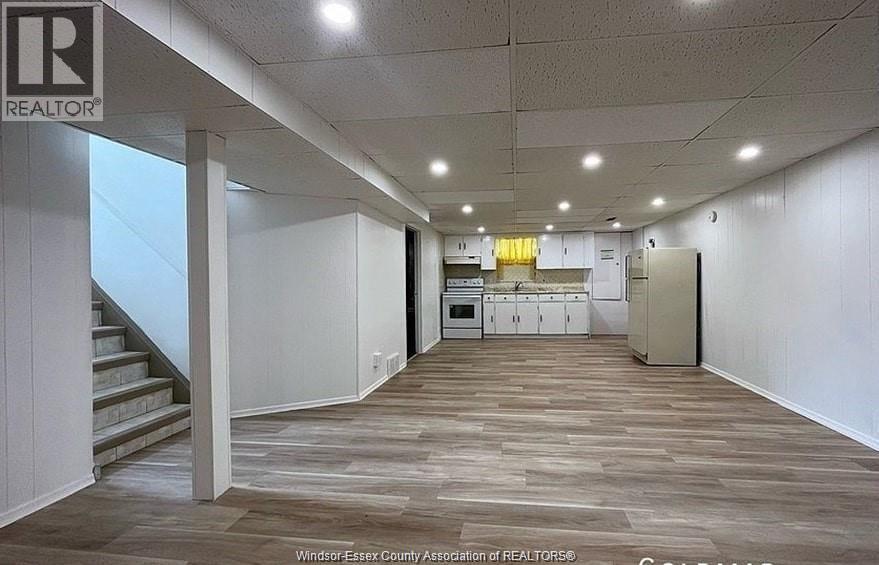 A long hallway with a staircase on the left and a kitchen area on the right.