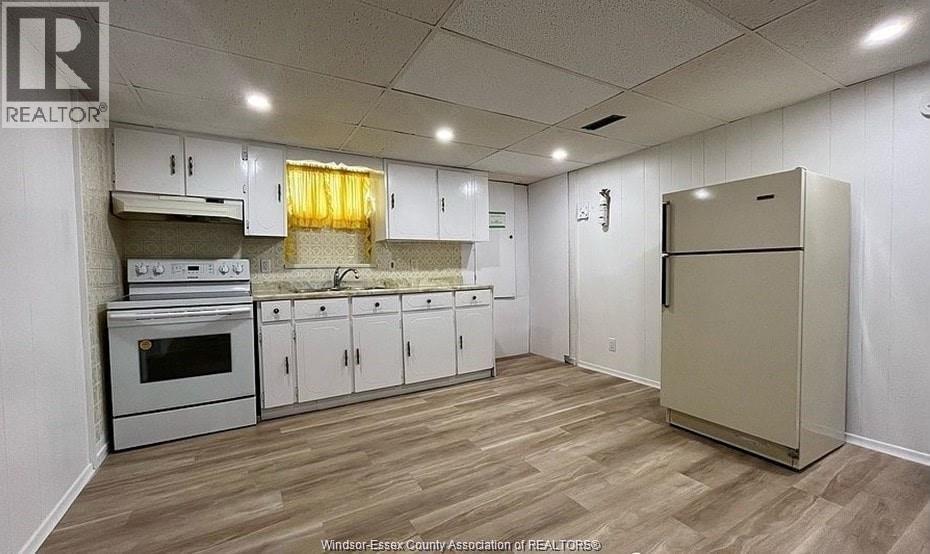 A kitchen with white cabinets and a wooden floor.