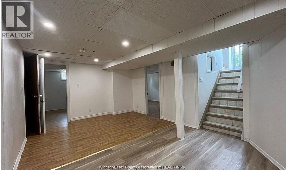 A spacious room with wooden floors and a staircase leading to another room.